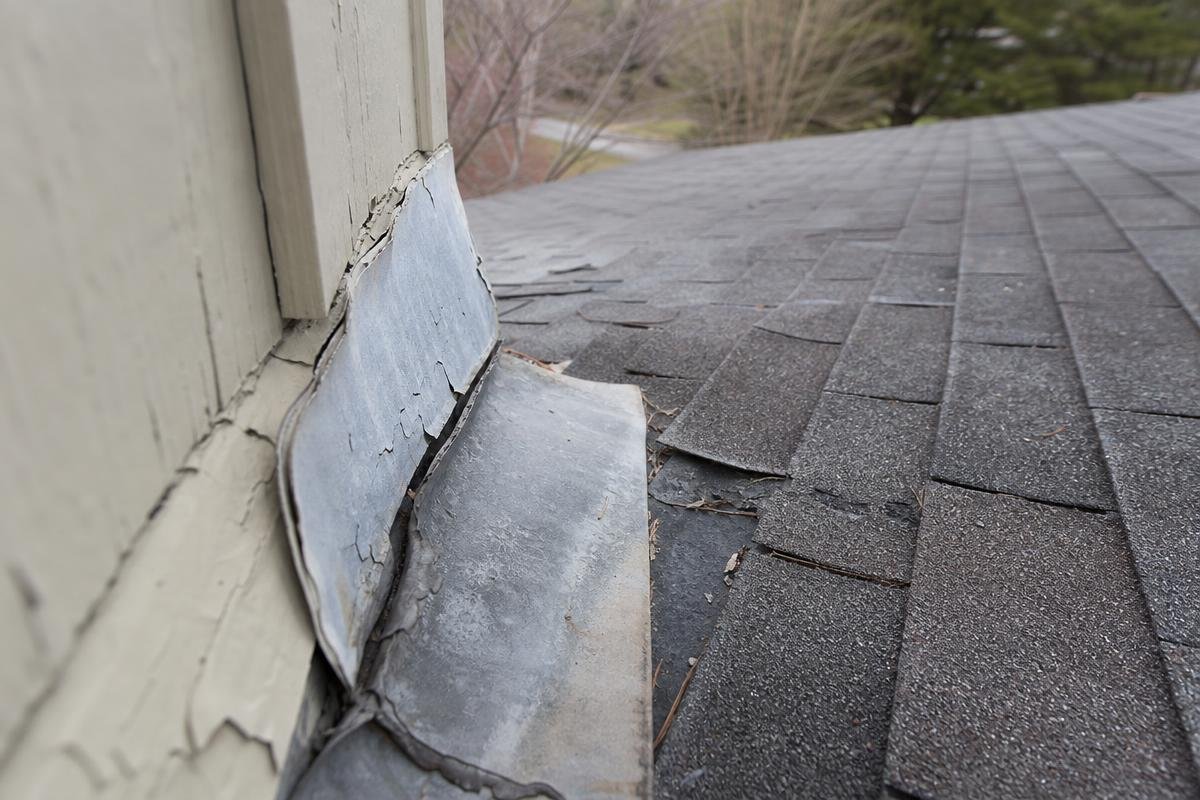 storm damage roof repair showing cracked flashing and worn shingles in Greer, SC
